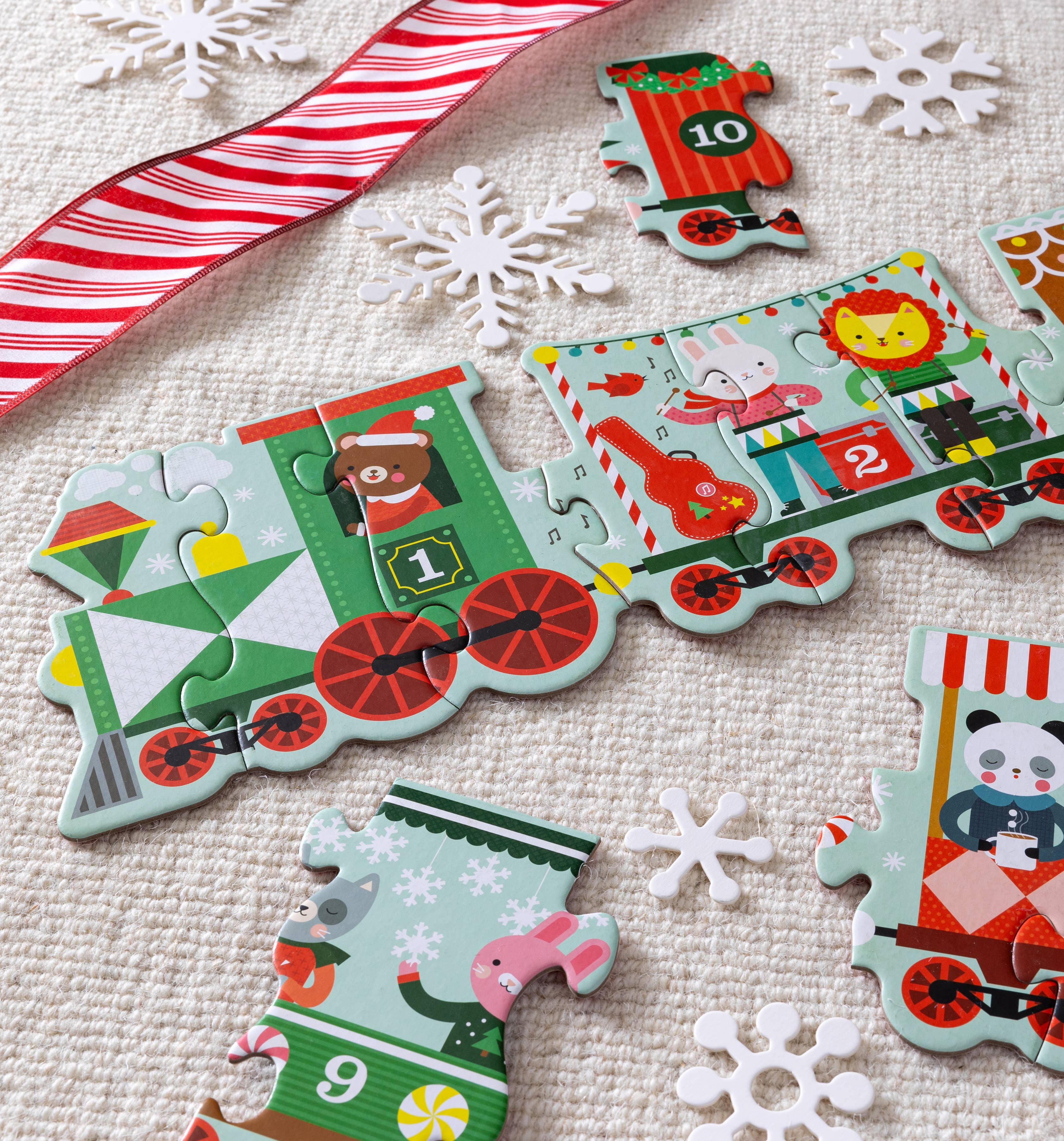 Children's train-themed puzzle with numbered car pieces on a textured surface with snowflakes and candy cane.