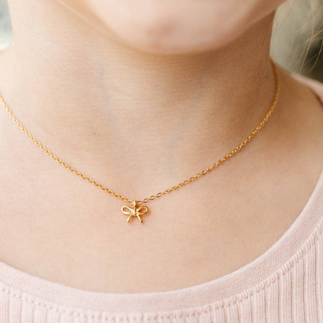 Gold bow pendant necklace from Pip Pop Post with delicate chain, perfect for stylish accessories and everyday wear.